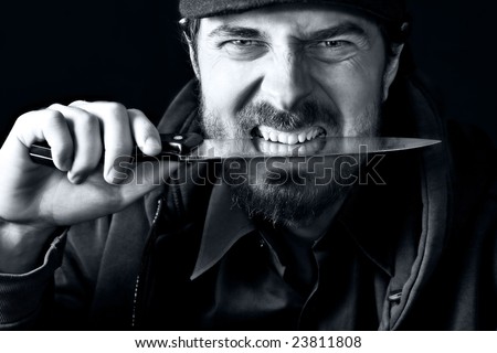 Tough angry guy biting from sharp knife