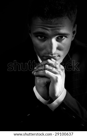 Sad young man in the dark praying to God