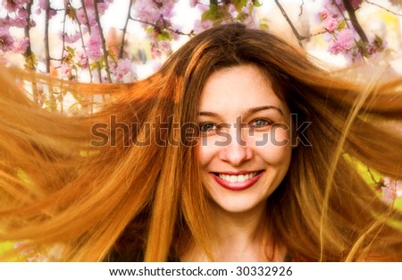 Happy woman with beautiful long hair and flowers in background