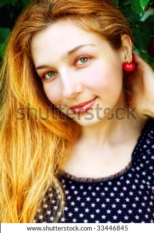 Happy joyful woman with cherry fruit at her ear