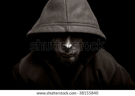Scary evil man with hood in darkness