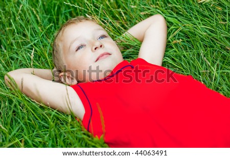 Pensive kid day dreaming in fresh grass
