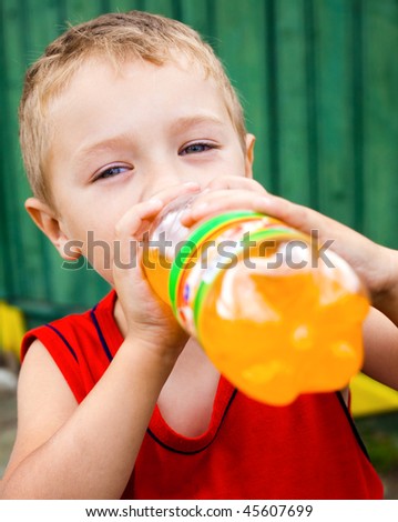 Thirsty child drinking unhealthy bottled orange soda