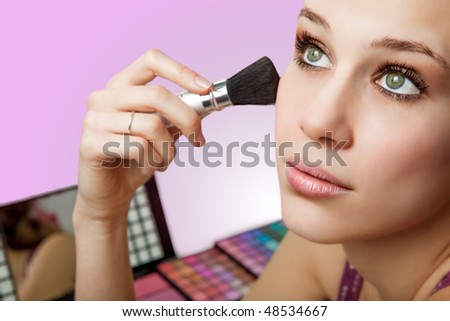 Makeup and cosmetics - beautiful woman using blush brush