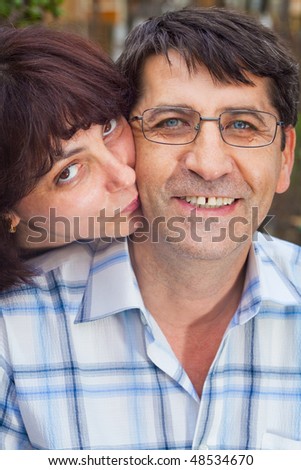 Family portrait of wife kissing her happy husband