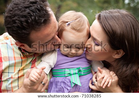 Kiss of love - happy parents with their cute baby girl