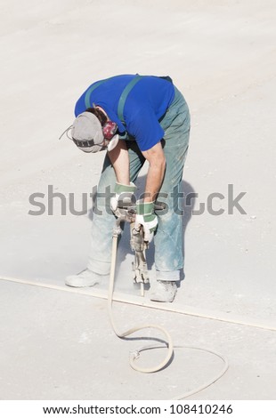 Worker wearing ear and breathing protection using a handheld hydraulic hammer