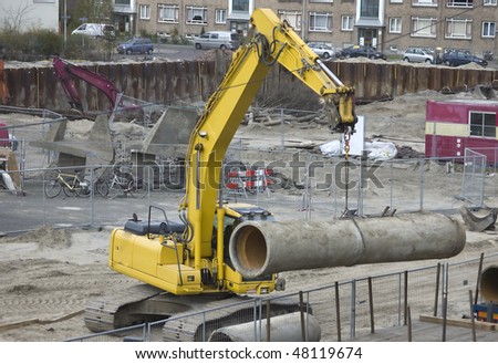 Excavator hoisting a sewer pipe