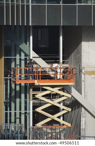 Painters wearing safety harness on a scissor lift