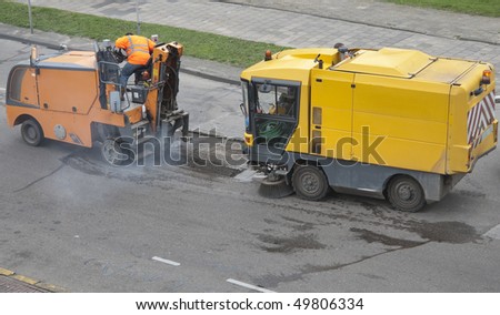 Repair machines fixing a pothole in a road caused by frost