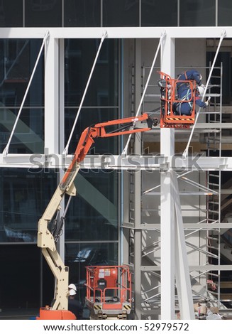 Workers wearing safety harnesses on an aerial access platform at a construction site