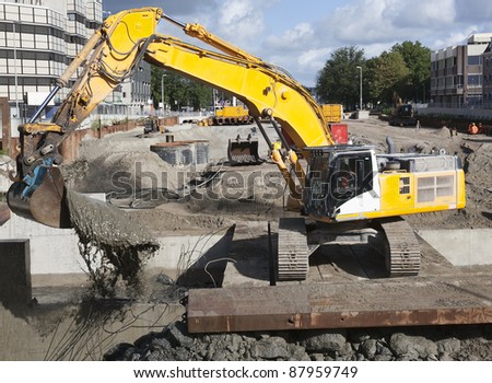 Excavator scooping mud on a urban construction site