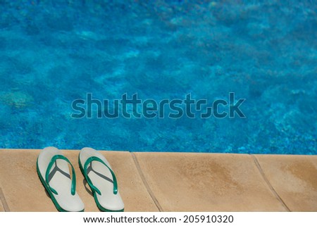 Pair of flip flop thongs on the side of a swimming pool