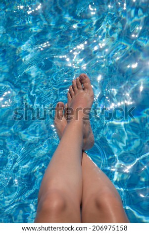Female legs in clear transparent blue water