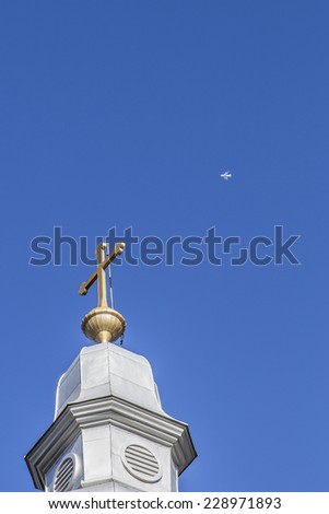 Church tower isolated on a blue sky and a plane passing in the background