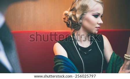 Beautiful retro chic blonde girl in black dress wearing pearls. Vintage style. Fashion colors