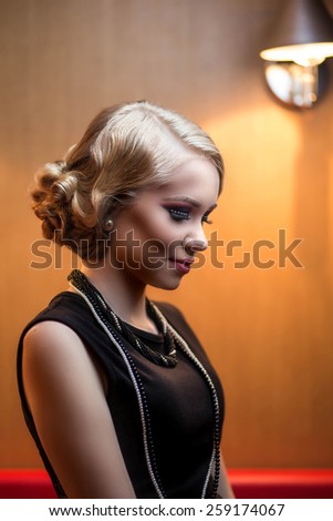 Beautiful retro chic blonde girl in black dress wearing pearls. Beauty Retro Woman Portrait. Glamour Lady. Vintage styled Girl with perfect make up and hairstyle
