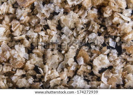 Pile of welsh oak smoked sea salt flakes on dark slate background. The salt is from Anglesey, Wales, United Kingdom, granted EU protected status in 2014. Close up.