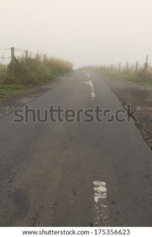 Top of hill, road and fences disappearing into low lying cloud. Eggardon Hill, Dorset, England, United Kingdom.