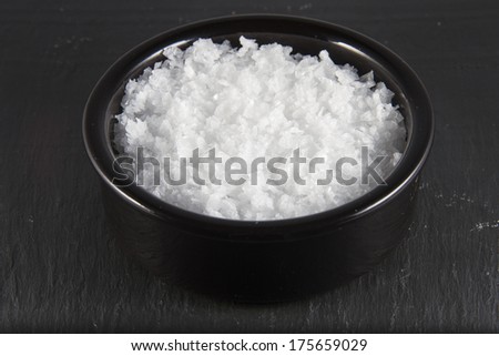 Welsh sea salt flakes on dark slate background. The salt is from Anglesey, Wales, United Kingdom, granted EU protected status in 2014. Close up.