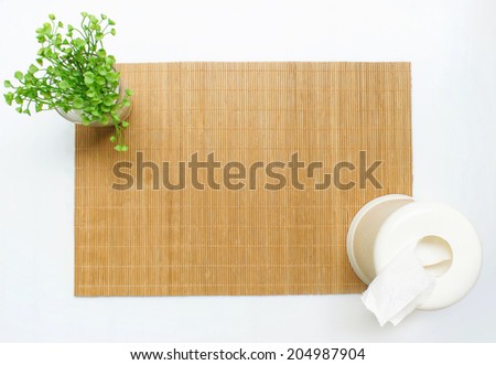 Bamboo table mat with a small plant and a tissue box