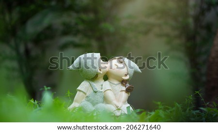Cute ceramic dolls on green meadow (love concept)