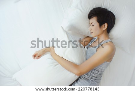 Asian woman sleeping in white bed, view from above