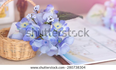 Blue and violet small flowers in basket, placing on white desk