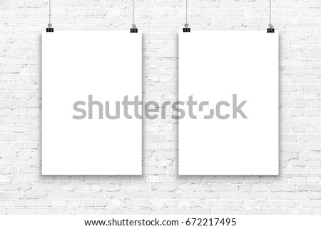 Two blank paper poster mockup on a white brick wall.