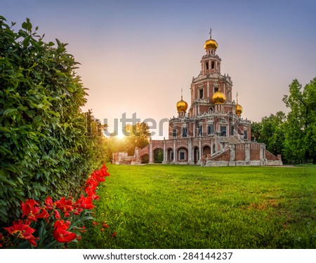 Red tulips at the temple with gold domes in the sunset light of the sun