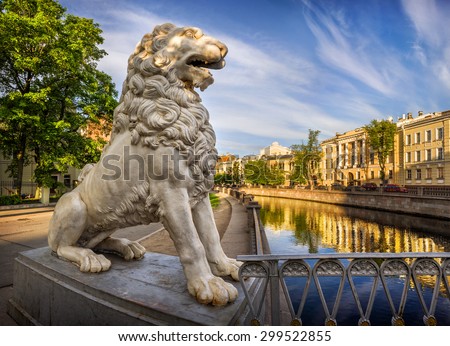 White lion statue on the bridge, and houses along the canal in the morning light