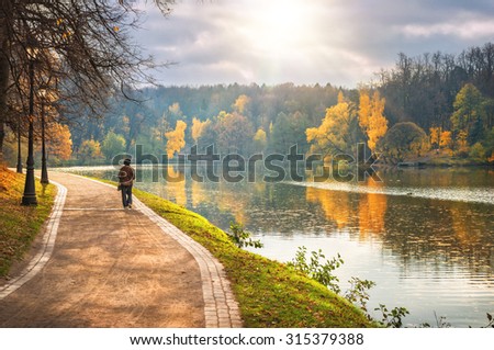 Golden autumn in the city park near the river and grandmother for a walk