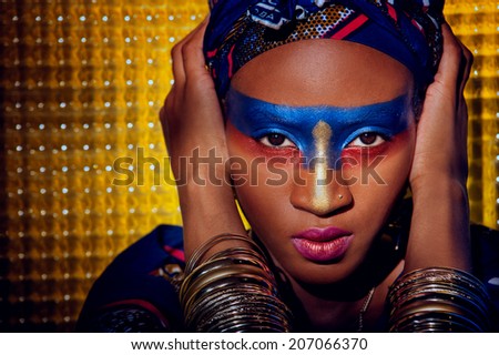 beautiful black woman with color makeup with gold ornamentation,   blue-red with gold makeup