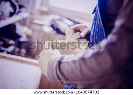 Worker uses a manual grinder. Toned image. Process of manual sanding of furniture stock in the carpentry shop
