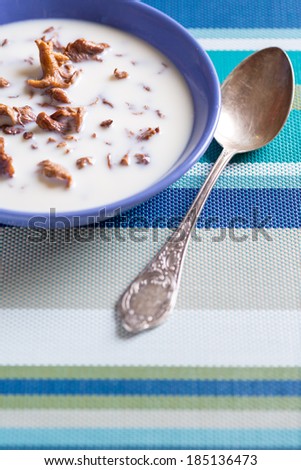 Mushroom milk soup in blue bowl with vintage spoon
