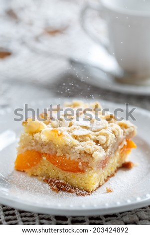 peach pie slice on white plate with powdered sugar