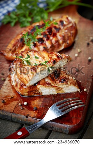 prepared on grill chicken fillet on cutting board with parsley and utensils