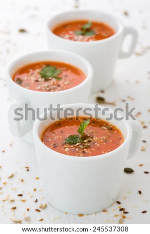 fresh tomato soup in cups with seeds and parsley. Vertical image.