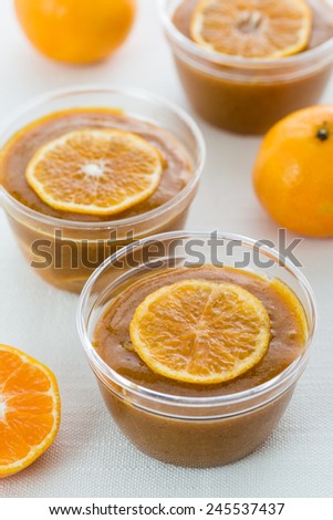 mandarin jam in glass jars with mandarin slices on white table. Vertical image.