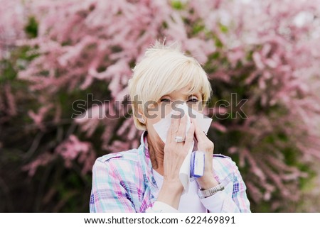 Vibrant blonde middle aged woman sneeze - spring allergies