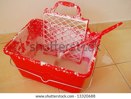 Red painter\'s bucket in the middle of his work. White color everywhere incl. floor though.