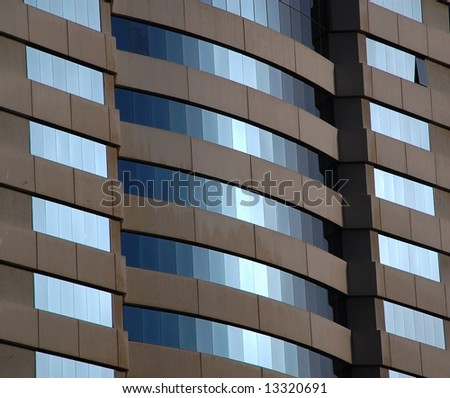 Windows in an anonymous office tower lighted during sunset.