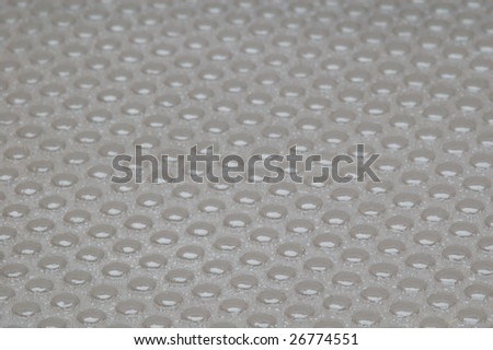 Close-up view on an anti skid plastic plate with lumps. It looks wet but its a just a texture.