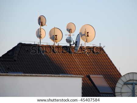 Five satellite dishes on top of the roof in a sunset light