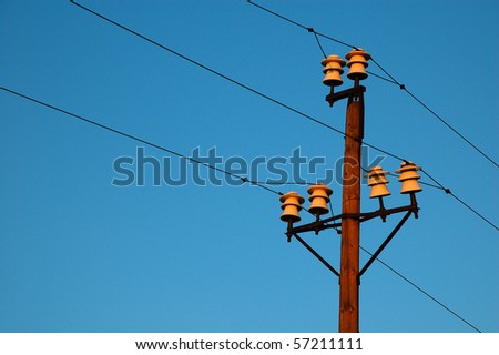 Head of pole of a high voltage overhead line in red sunset light.