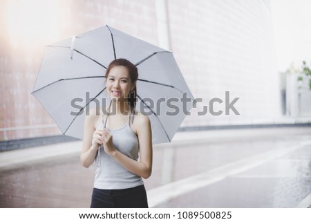 Charming beautiful young woman. Attractive beautiful lady hold an umbrella. It’s rainy day. Lovely girl is walking at city when light rain. It’s rainy season. She look so relaxed and happy. copy space