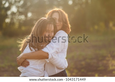 happy mother with her daughter hugging a teenager in the summer in the setting sun