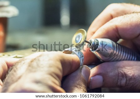 Male jeweler polishing a silver ring with a copper wire brush mounted on a flex shaft, motion effect.