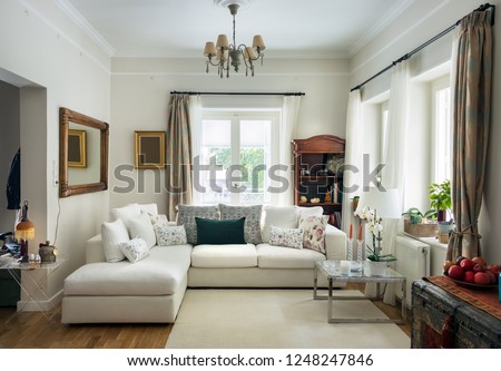 Large living room very bight  with oak wooden floor, four seats sofa, white carpet and retro objets, Greece.