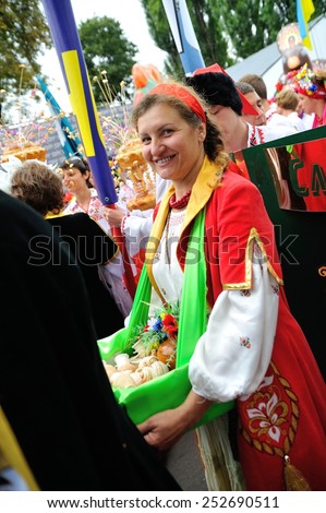 KIEV, UKRAINE - AUGUST 24: ?n ukrainian woman with a basket of goods in her hands and many people in national costumes around her at Independence Day on August 24, 2013 in Kiev, Ukraine